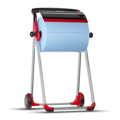 A Tork 652008 roll dispenser floor stand Performance W1, brand TORK – Essity Professional Hygiene Germany GmbH, holds a large paper towel roll and is equipped with wheels for mobility. The dispenser features an elegant red-black design and has a robust metal frame and a serrated edge to facilitate tearing off the sheets.