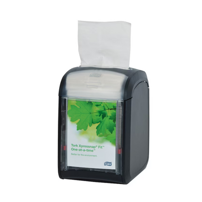 A Tork Xpressnap Fit® 272900 table dispenser for napkins by TORK - Essity Professional Hygiene Germany GmbH features an elegant black table design with a transparent front plate with a green leaf pattern. Inside, white napkins are neatly arranged, with one ready for use. This dispenser effectively manages napkin consumption by dispensing one napkin at a time.