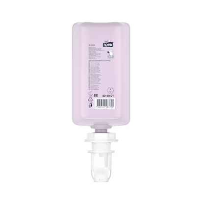 A pink, rectangular bottle of Tork luxurious liquid soap with a white cap is displayed. It shows product details and a barcode and contains luxurious liquid soap with natural ingredients, enriched with magnolia extract. This refill is positioned upside down for easy insertion into a dispenser and is part of a set from the TORK brand of Essity Professional Hygiene Germany GmbH.
