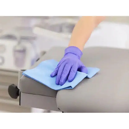 A person wearing a purple glove improves their cleaning performance by using a Vileda r-MicronQuick microfiber cloth - 5 cloths from Vileda GmbH on a gray surface.