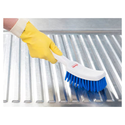A person with a yellow rubber glove uses a Vileda Professional short-handled brush blue – 30 cm| Package (1 piece) by Vileda GmbH with high-quality bristles to clean a ribbed metal surface.