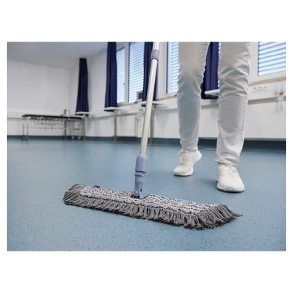 A person in white shoes and pants is mopping a blue floor with a Vileda GmbH Professional Swep Duo r-MicroCombi Mop - 50 cm in a room with closed blinds and blue curtains. A folding table stands nearby and a radiator is under the windows.