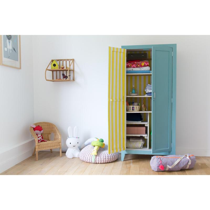 In a children's room, there is a blue wardrobe, toys, and a wicker chair. On the shelf, there are small items next to the 3M Deutschland GmbH Scotch® painter's masking tape for delicate surfaces (100% PEFC SGSCH-PEFC-COC-110078).