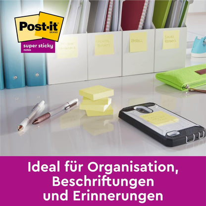 On a desk are 3M Post-it® Super Sticky 100% Recycled Notes, folders, pens, and a smartphone. The sticky notes are on the phone, the desk, and the folders. The folders are labeled on a shelf. Text: "Ideal for organization, labeling, and reminders.