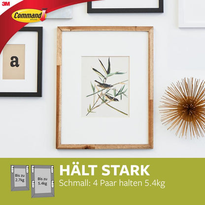 A framed plant print hangs on a white wall with other frames and a gold object. Below, the Narrow Command™ Picture Hanging Strips (M) 17207 from 3M Deutschland GmbH are advertised for their residue-free removable and strong holding power.