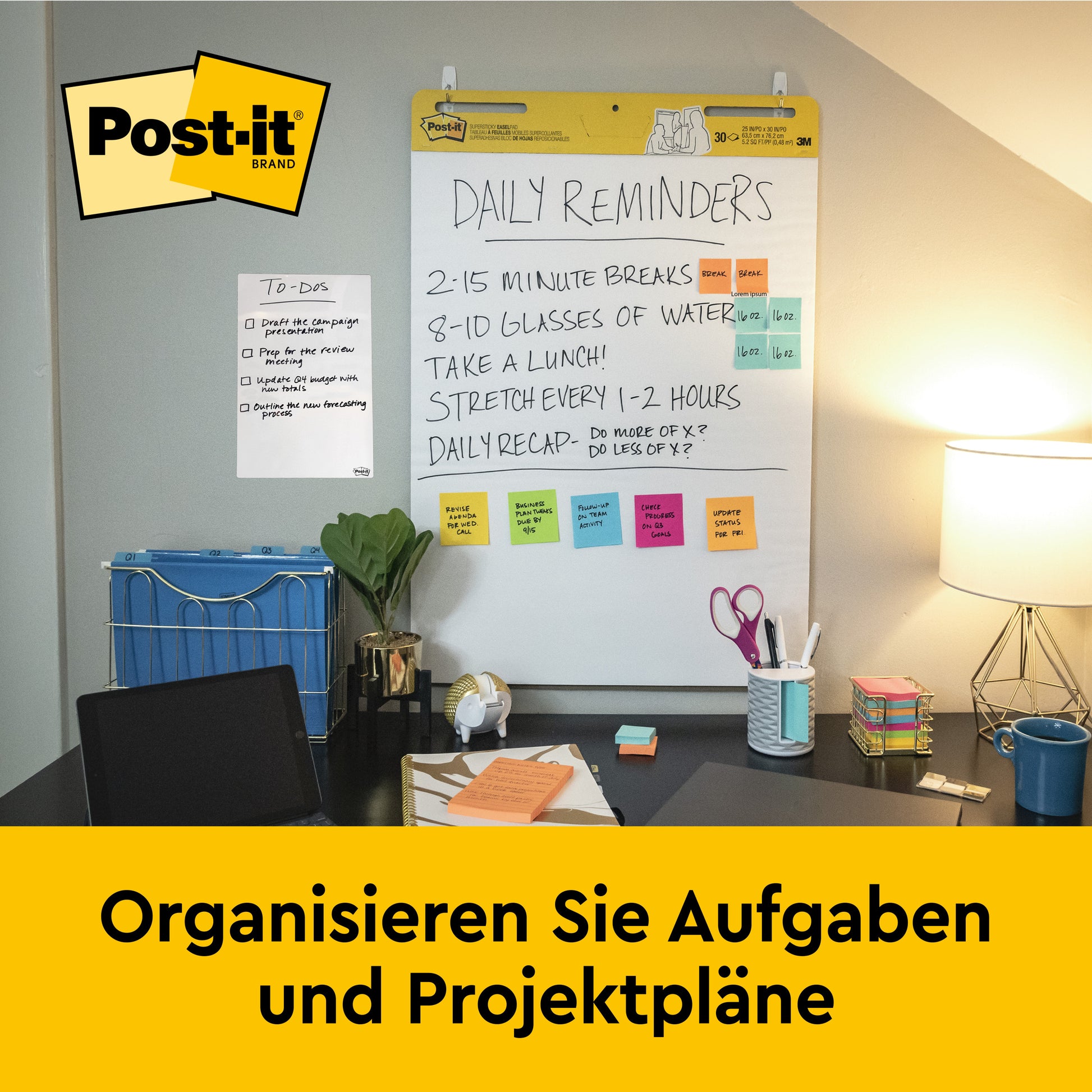 Ein Schreibtisch mit Büromaterialien steht vor einer Wand, an der ein Post-it® Super Sticky selbsthaftendes Meeting Chart/Flipchart von 3M Deutschland GmbH (Weiß, 63,5x76,2 cm) hängt. Unten steht: "Organisieren Sie Aufgaben und Projektpläne.