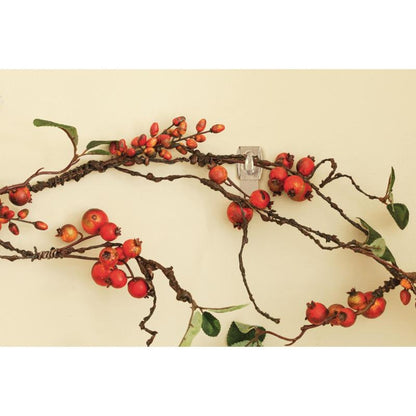A decorative branch with red berries and green leaves hangs on a light wall, attached without a trace with the Command™ Mini Hook, transparent, with transparent strips (17006CLR) from 3M Deutschland GmbH.
