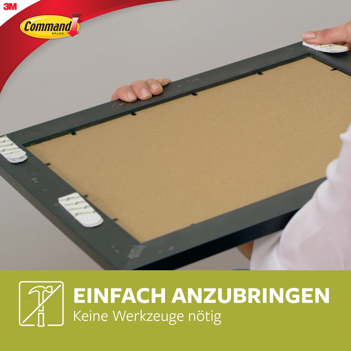 With the small and medium-sized Command™ Picture Hanging Strips, value pack 17203 from 3M Deutschland GmbH, a picture frame is mounted on the wall without nails. Several white strips are visible on the back of the frame. Text: "Simply attach, no tools needed.