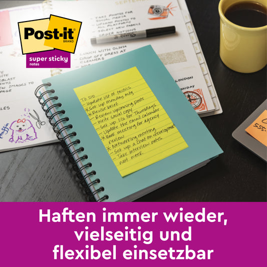 Eine gelbe Post-it® Super Sticky Meeting Note (203 mm x 153 mm, 70 Blatt, farbig sortiert) von 3M Deutschland GmbH klebt auf einem blauen Spiralnotizbuch auf einem Schreibtisch mit Papieren und Kunstzubehör. Haften immer wieder, vielseitig und flexibel einsetzbar.