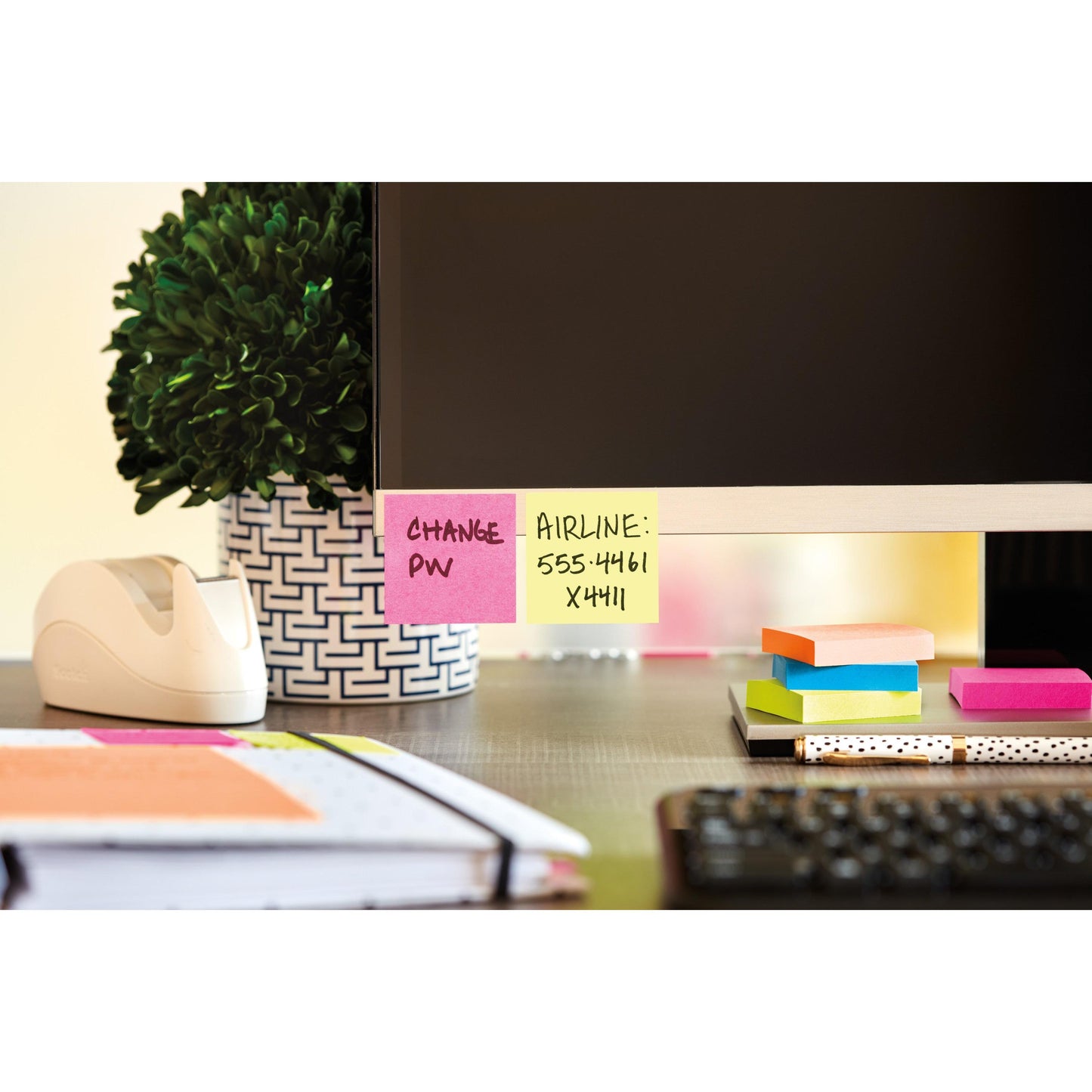 A computer monitor on a desk with self-adhesive notes - one says "CHANGE PW" and another has an airline's phone number. Also on the desk: a plant, a tape dispenser, and 3M Post-it® Notes Cube 636-B, Yellow, 76x76 mm, 450 sheets.