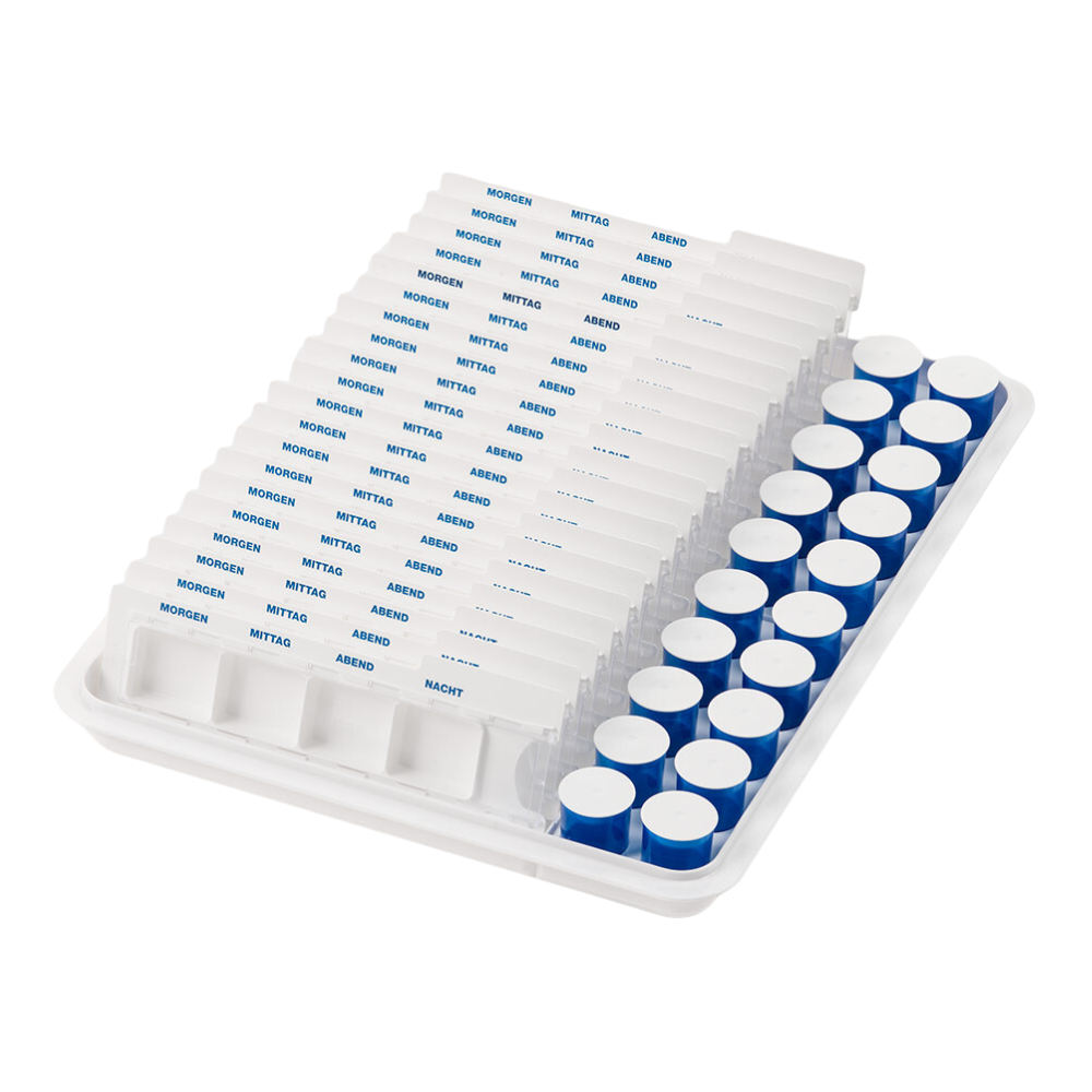 A mevipas dispenser cup tray from Helmut Schwarz GmbH consists of a white tray on which there is a medication organizer with rows of tablet compartments labeled in German: "Morning", "Noon", "Evening" and "Night". Next to it are cylindrical containers with blue lids, perfect for efficient medication storage in the care sector.